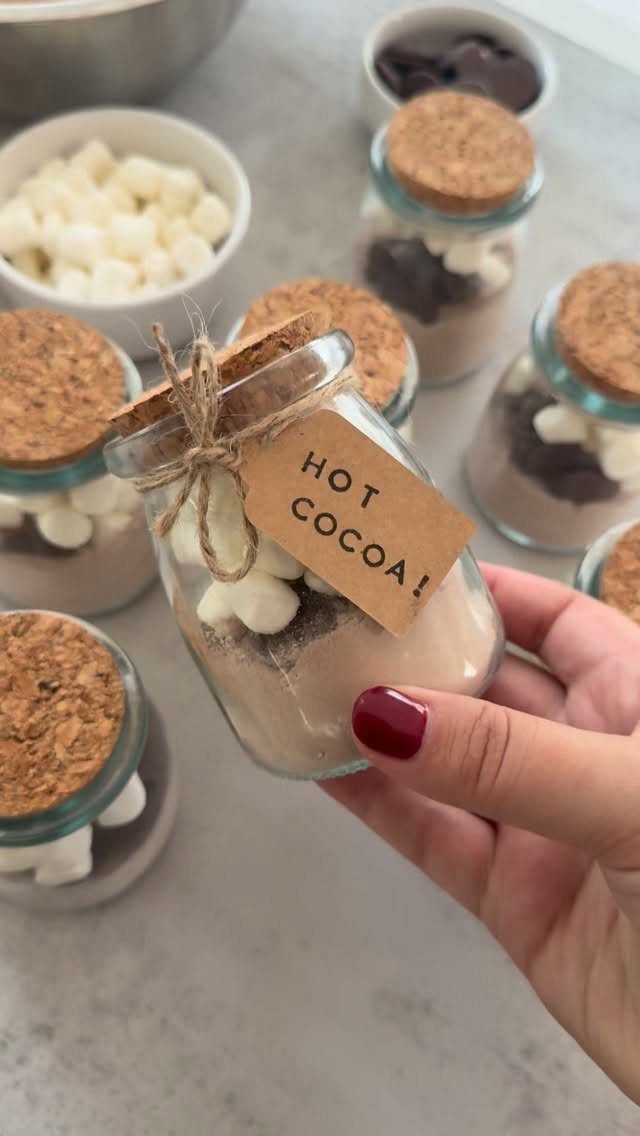Glass jars filled with layered hot chocolate mix, cocoa, and marshmallows with tags.