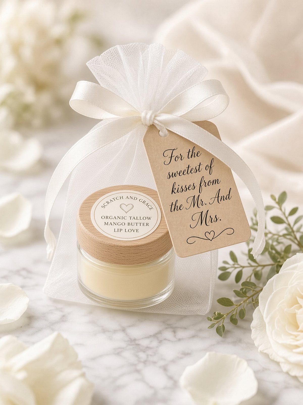 Lip balm in a glass jar with a wedding favor tag and tulle bag.