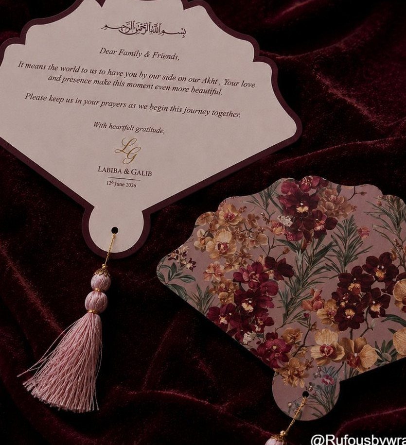 Floral patterned hand fan and personalized thank you card on red velvet fabric.