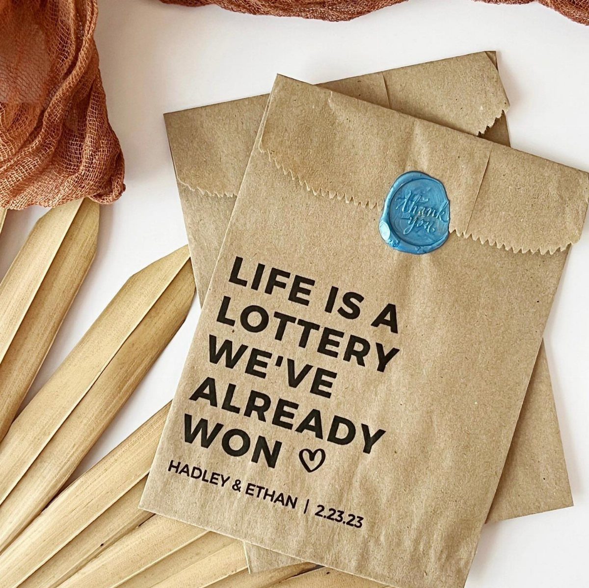Brown kraft paper envelopes with lottery themed wedding text and blue wax seal