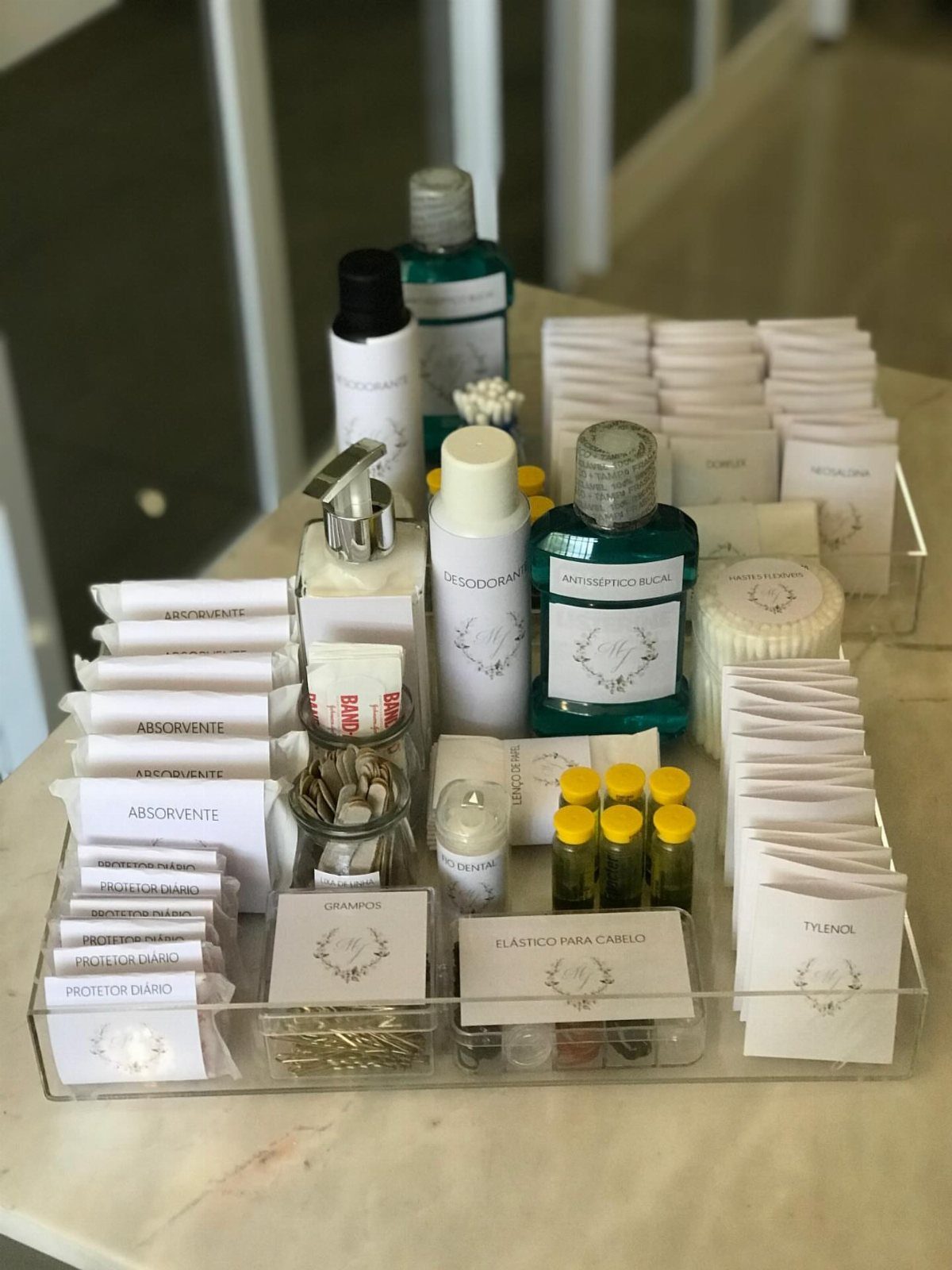 Acrylic tray of wedding bathroom amenities including toiletries and hygiene products on marble.