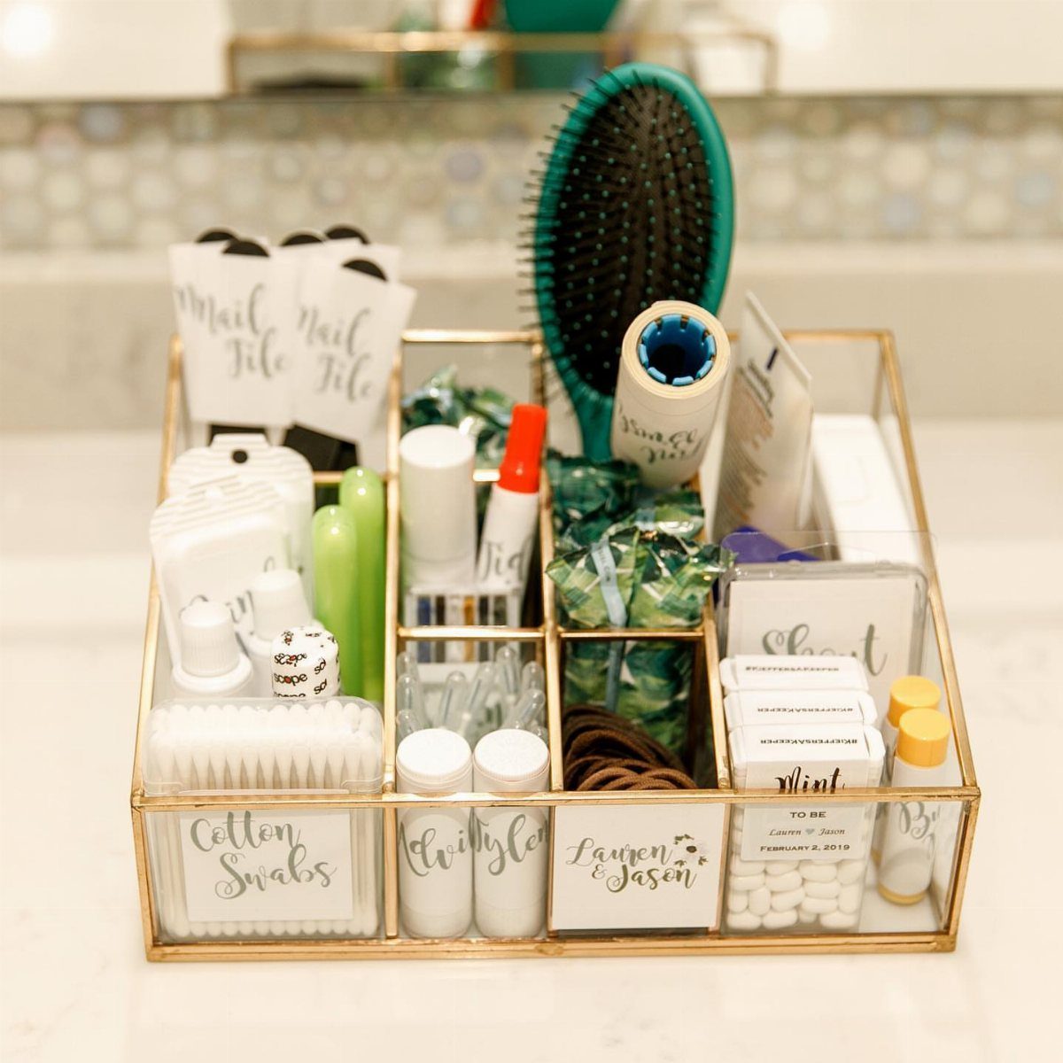 Gold wire basket filled with wedding bathroom amenities on a white marble counter.