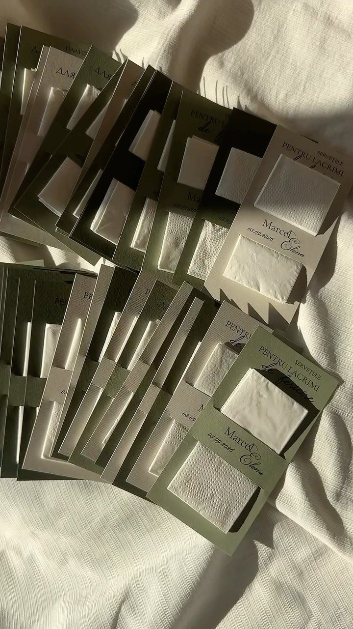 Individually packaged white cotton pads in olive green sleeves on white fabric.