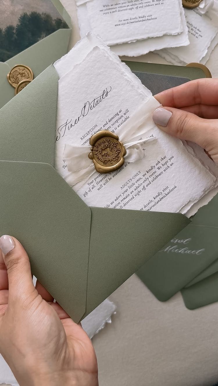 Sage green envelope with a deckle-edged invitation featuring elegant calligraphy and gold wax seal