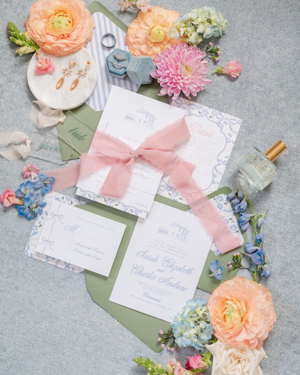 Wedding invitation suite with venue illustration, pink ribbon, and colorful spring flowers.