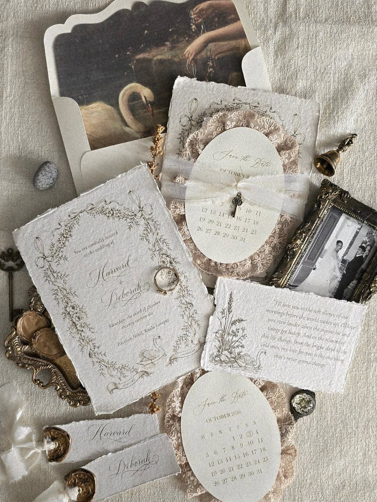 Vintage wedding invitations with deckle edges, floral borders, and a small gold bell.