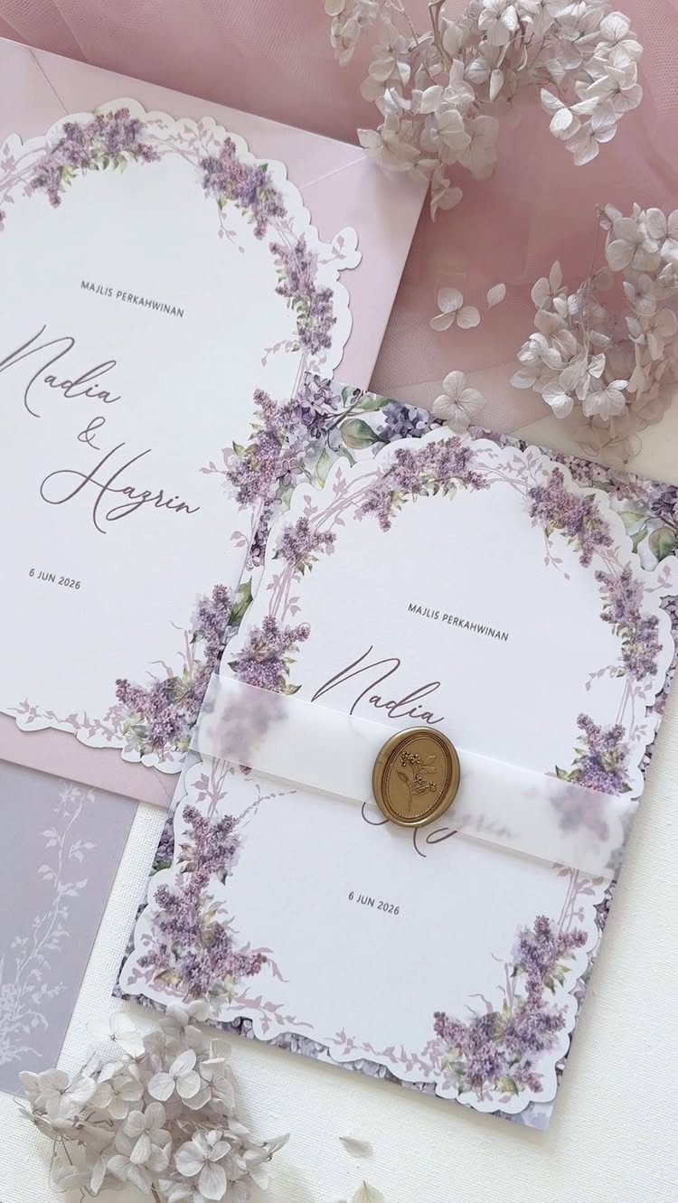 Scalloped edge wedding invitations with purple floral borders and a gold wax seal.