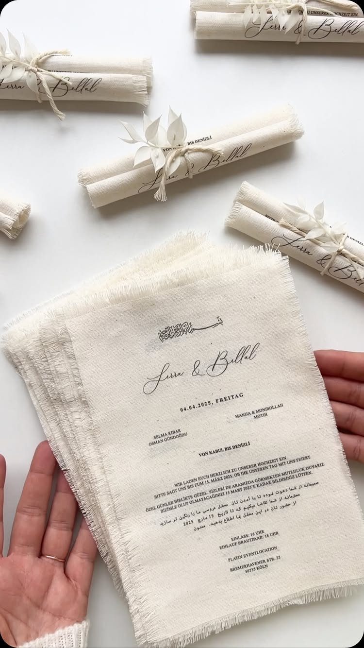 Fabric wedding invitations with frayed edges and rolled versions tied with twine.