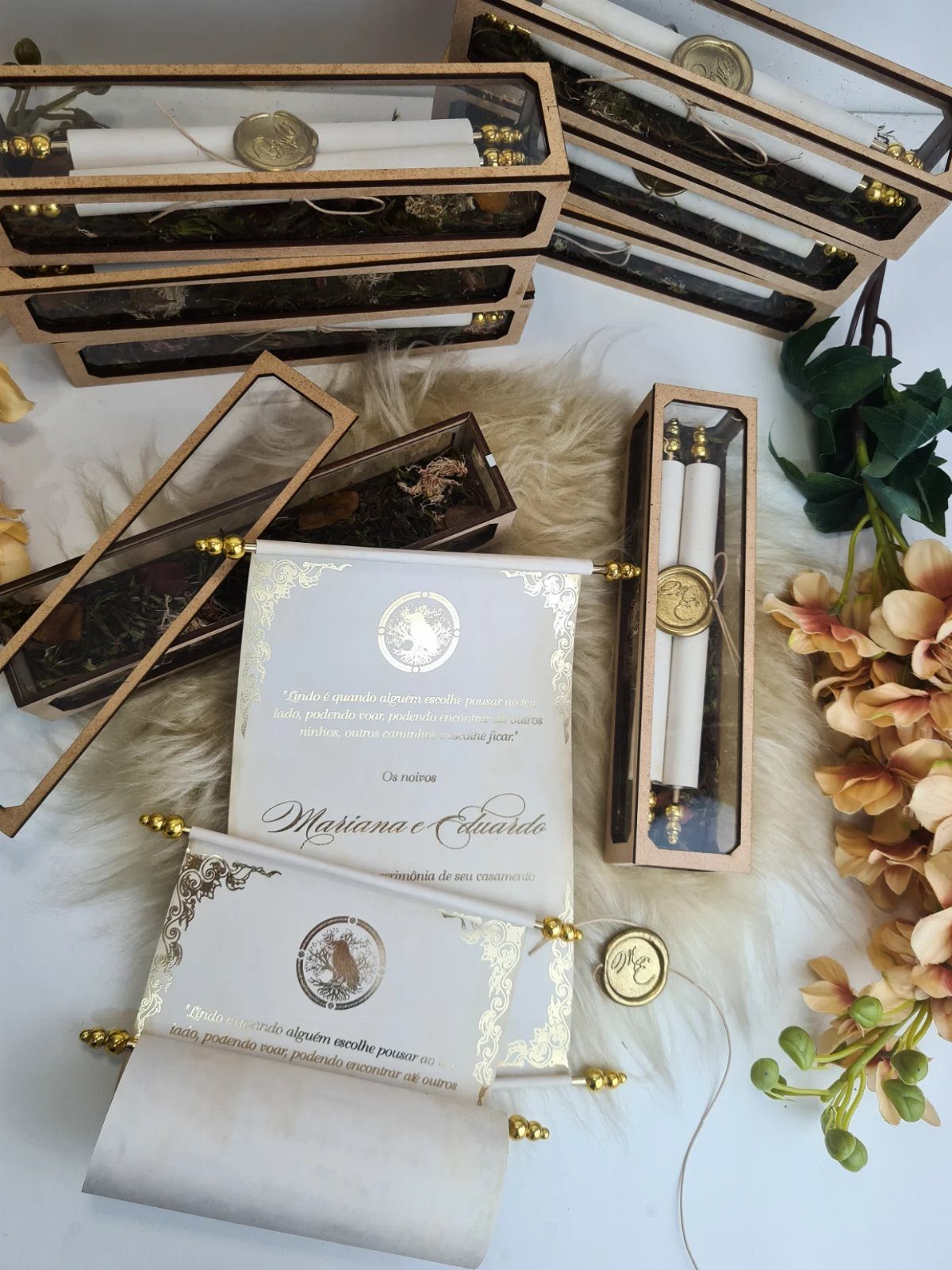 Scroll wedding invitations with gold details and wax seals in acrylic boxes.