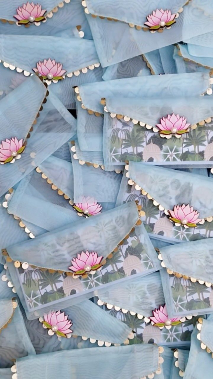 Light blue vellum envelopes with gold beaded edges and pink lotus flower accents.