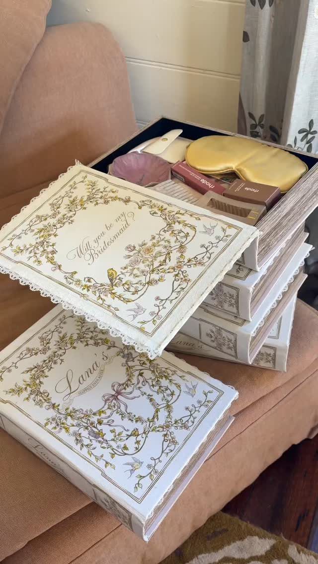 Book-shaped gift boxes with gold floral designs containing a yellow sleep mask.