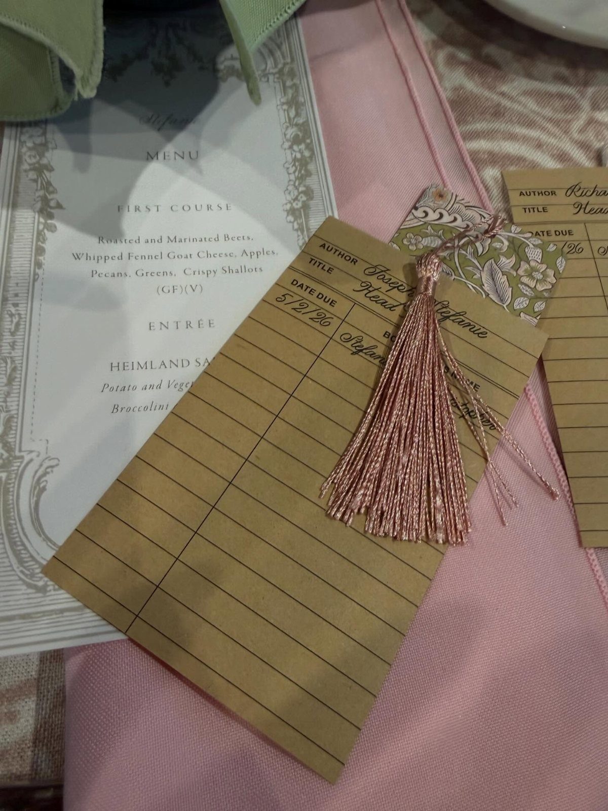 Vintage library card with a pink tassel resting on a pink wedding napkin.