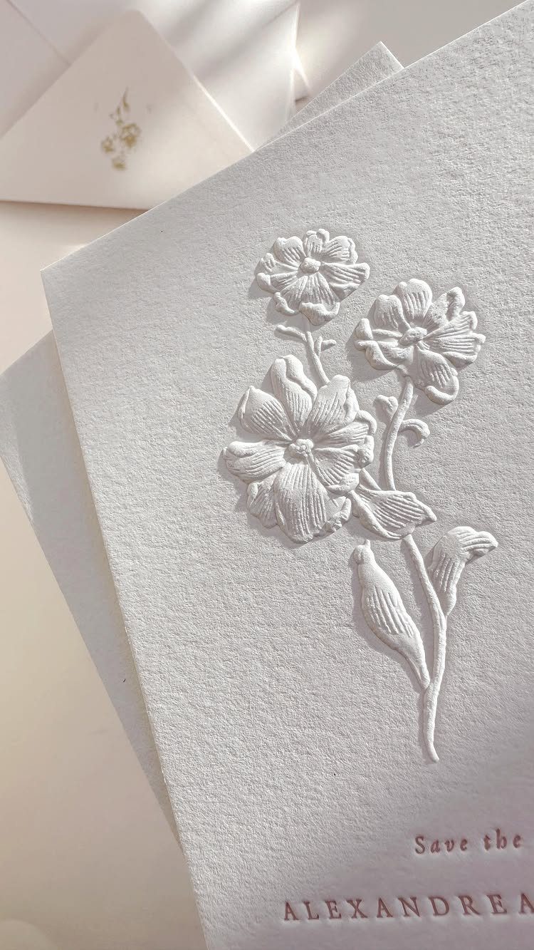 White textured card with embossed floral design and embossed name ALEXANDREA