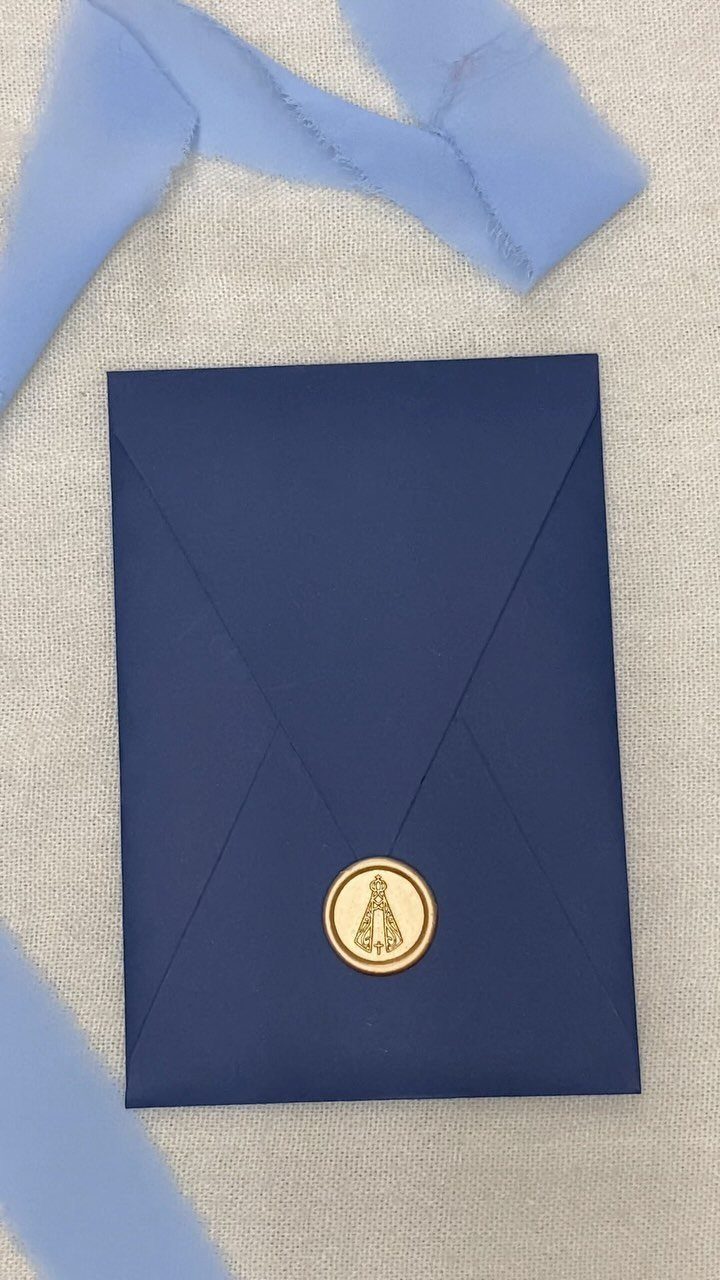 Dark blue envelope with a gold religious wax seal on grey fabric.