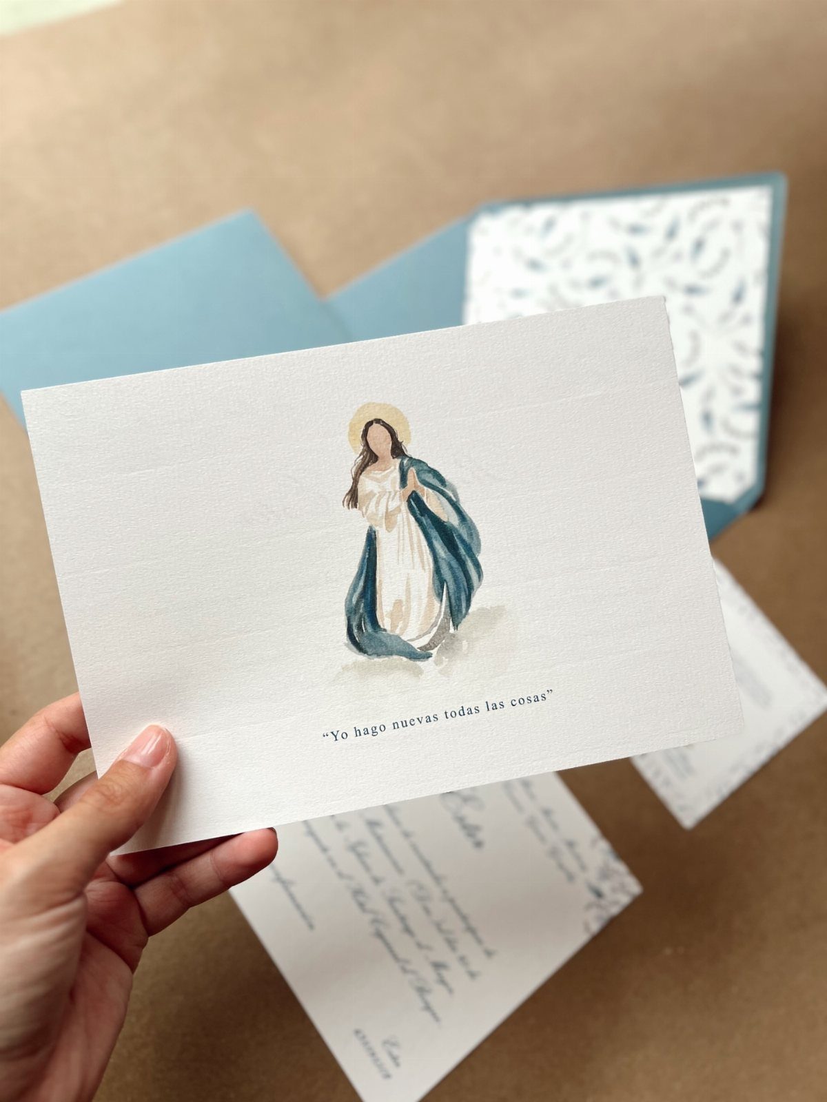 White invitation card featuring an illustration of the Virgin Mary in blue robes.