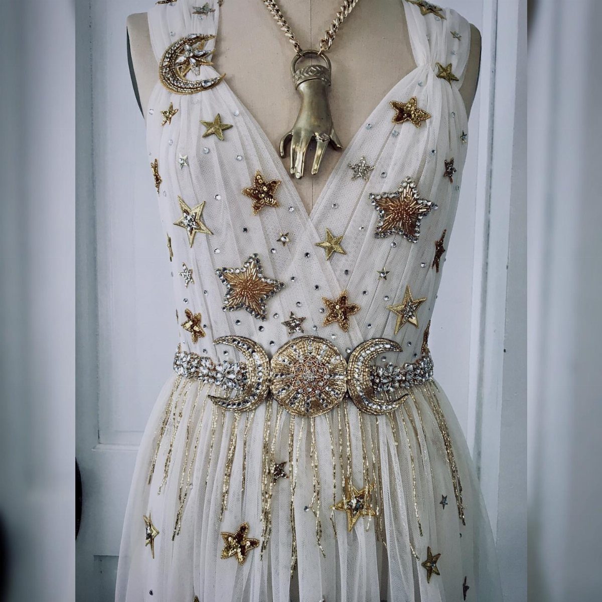 White dress on a mannequin decorated with gold stars and crescent moon sequins.
