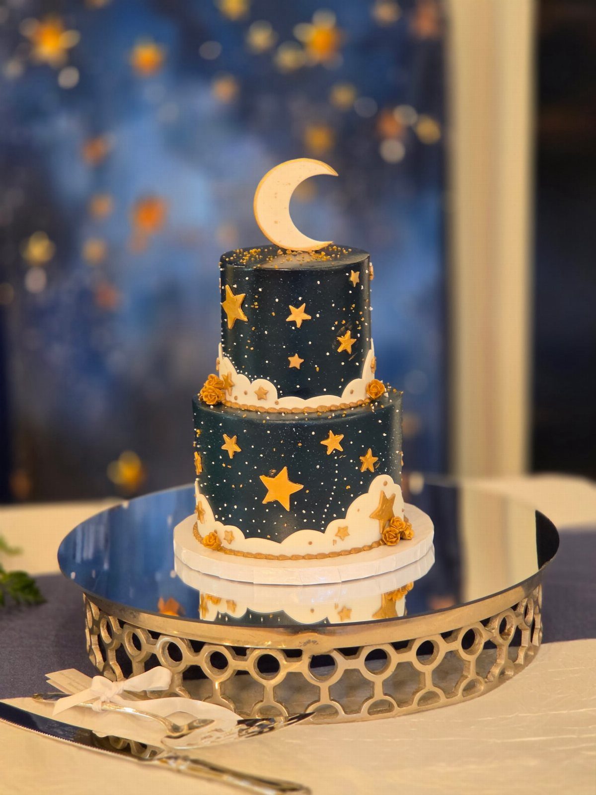 Navy blue celestial cake with gold stars and a crescent moon topper