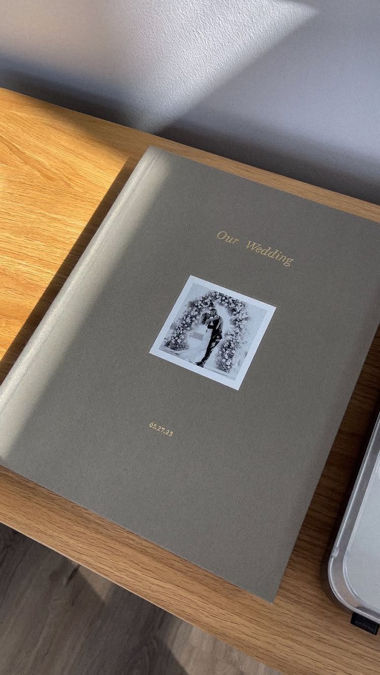 Grey wedding photo album with gold lettering and a couple's photo on wood.