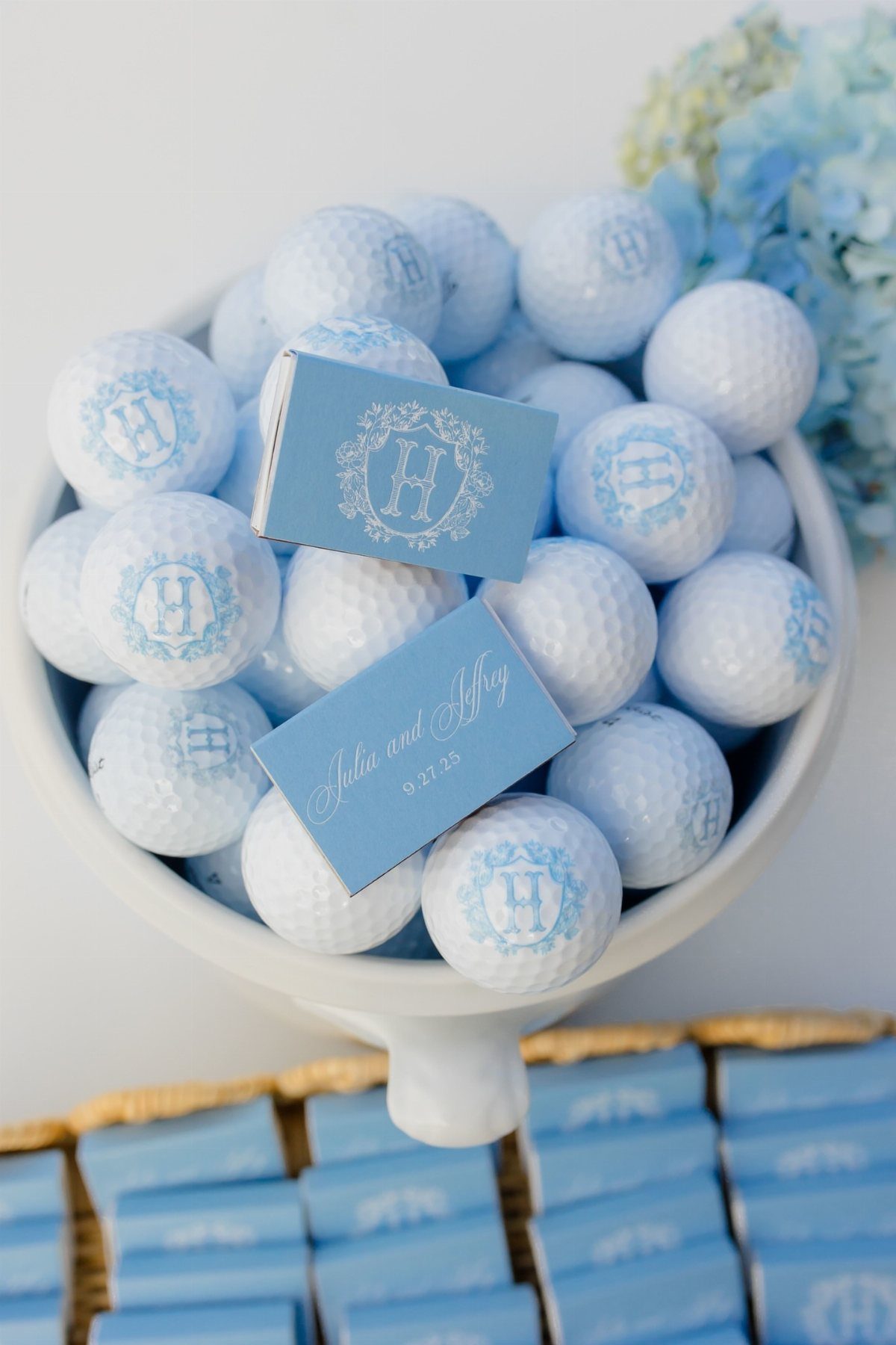 Monogrammed white and blue golf balls in a white bowl with blue cards