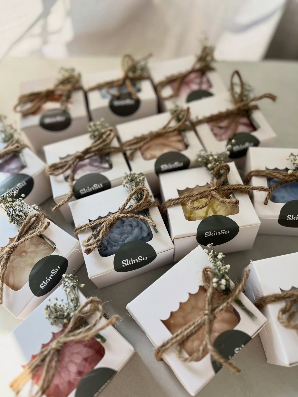 Handmade soap bars in white boxes tied with twine and baby's breath flowers.