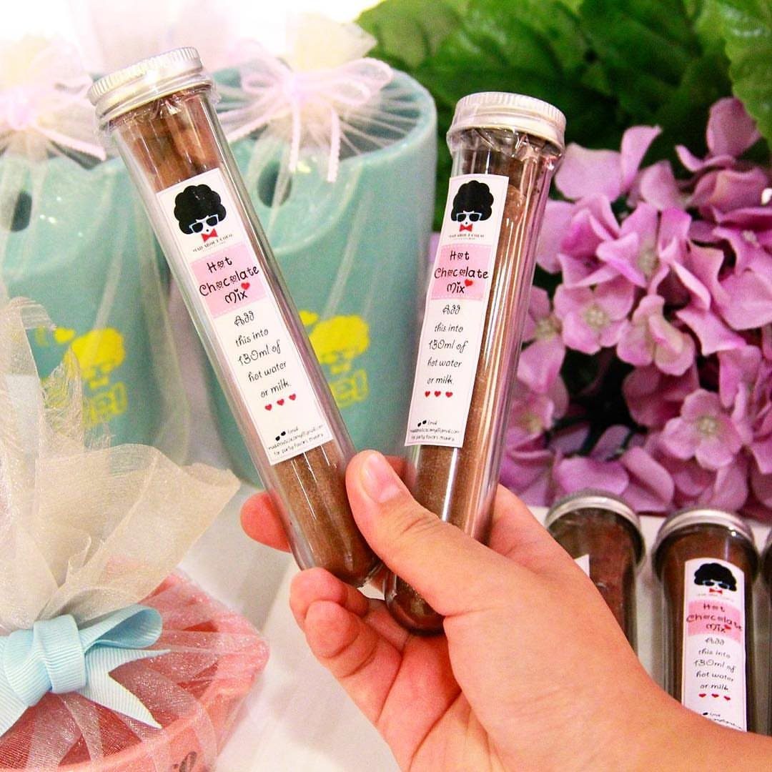 Two clear tubes filled with hot chocolate mix held by a hand.