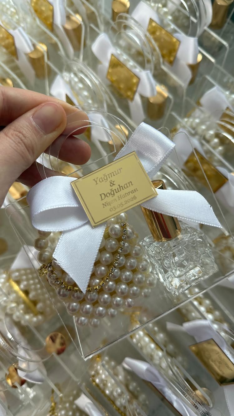 Clear favor box with perfume bottle, white pearls, and gold name tag
