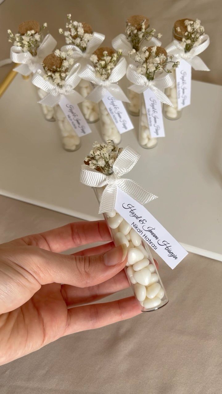 Small glass tubes filled with white candies, decorated with ribbons and baby's breath.