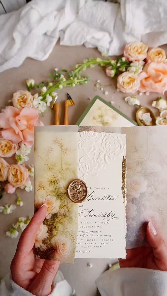 Wedding invitation with elegant script font, gold wax seal, and peach roses.