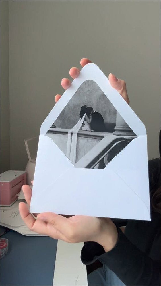 White envelope held open showing a black and white photo envelope liner.