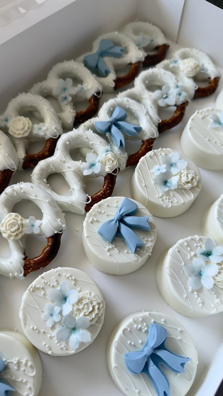 White chocolate covered pretzels and round treats decorated with blue and white flowers.