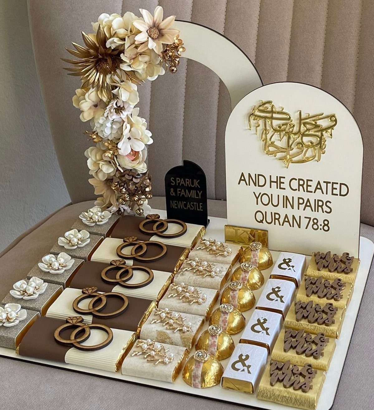 Wrapped chocolate bars with gold ring toppers on a white decorative display tray.