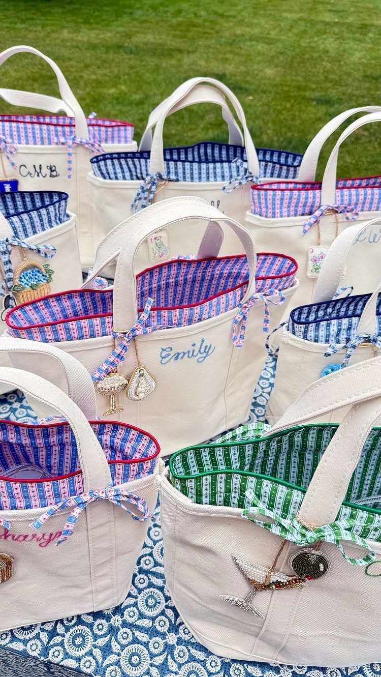 Personalized white canvas tote bags with colorful striped linings and embroidered names.