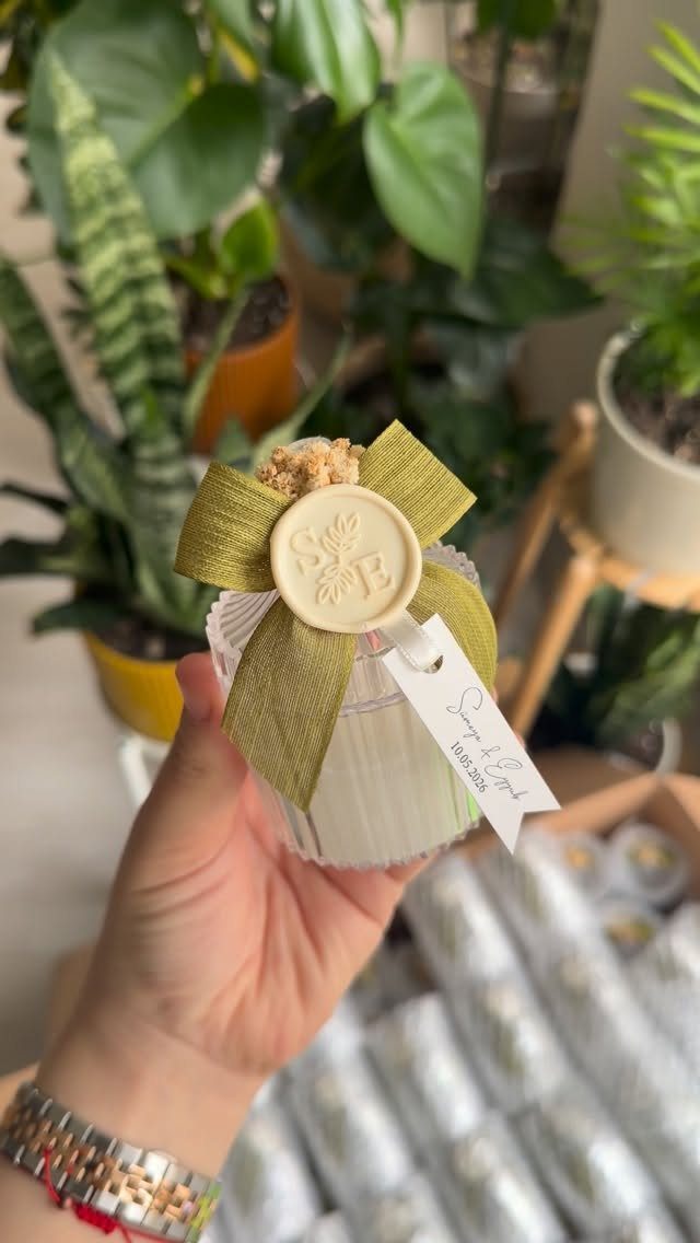 Small white candle in a ribbed jar with a green ribbon and wax seal.