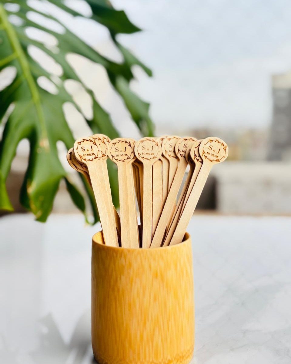 Wooden coffee stirrers with engraved tops in a yellow ceramic cup