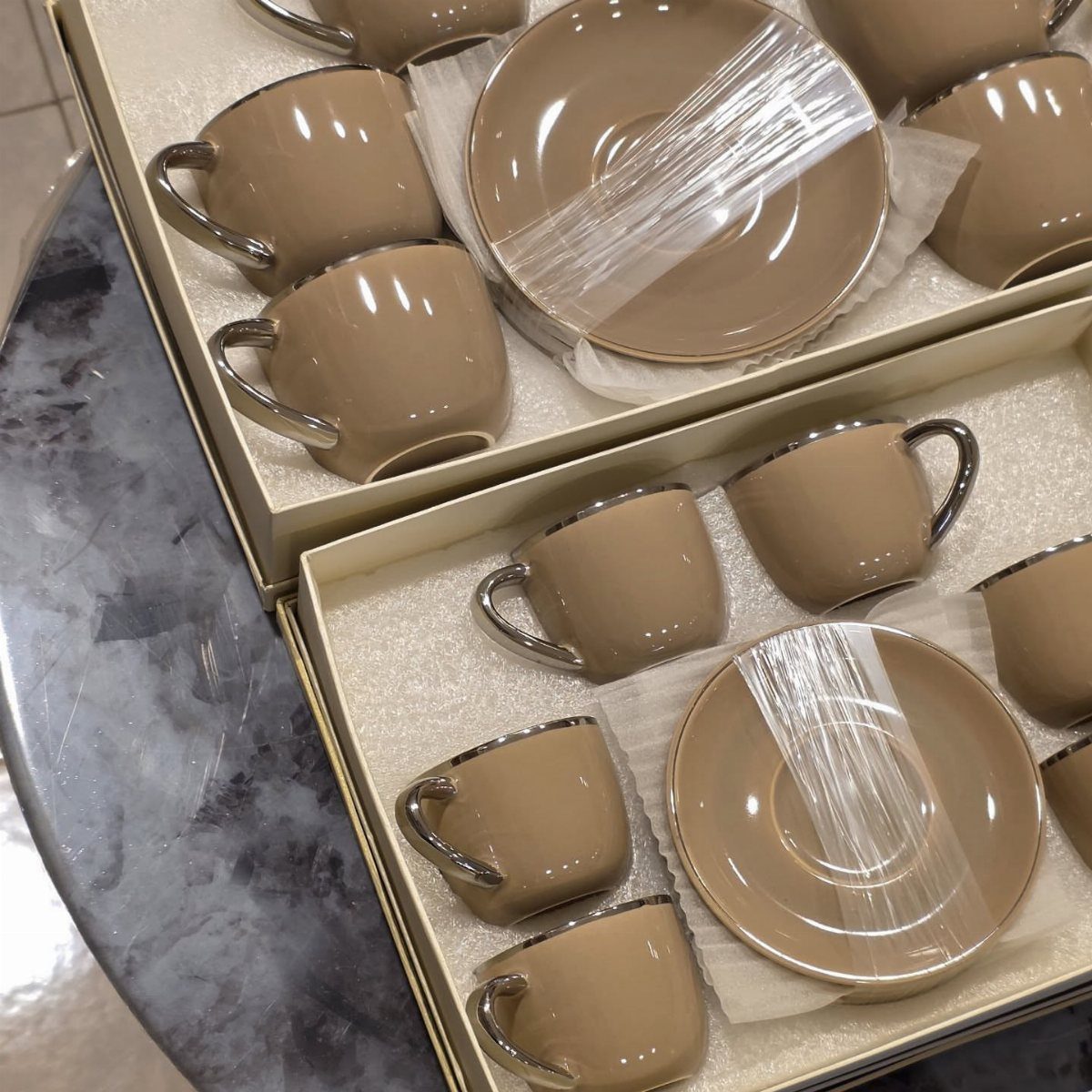 Tan ceramic espresso cups and saucers with silver rims in white gift boxes