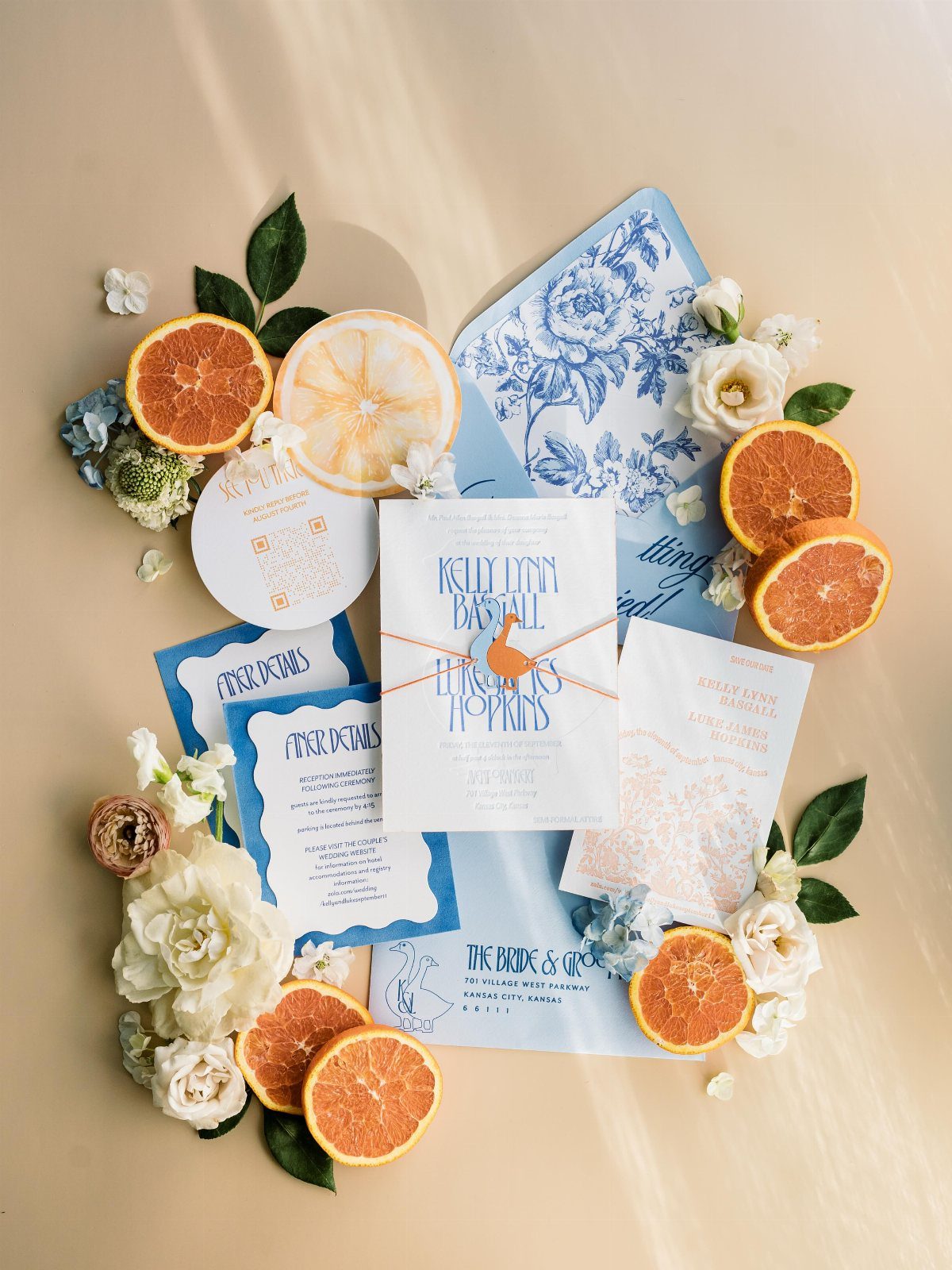 Wedding invitation suite with blue patterns, citrus slices, and white floral accents.