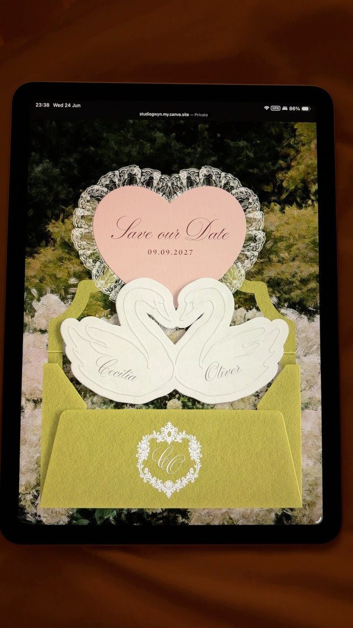Wedding invitation set with swan shapes and heart card displayed on a tablet
