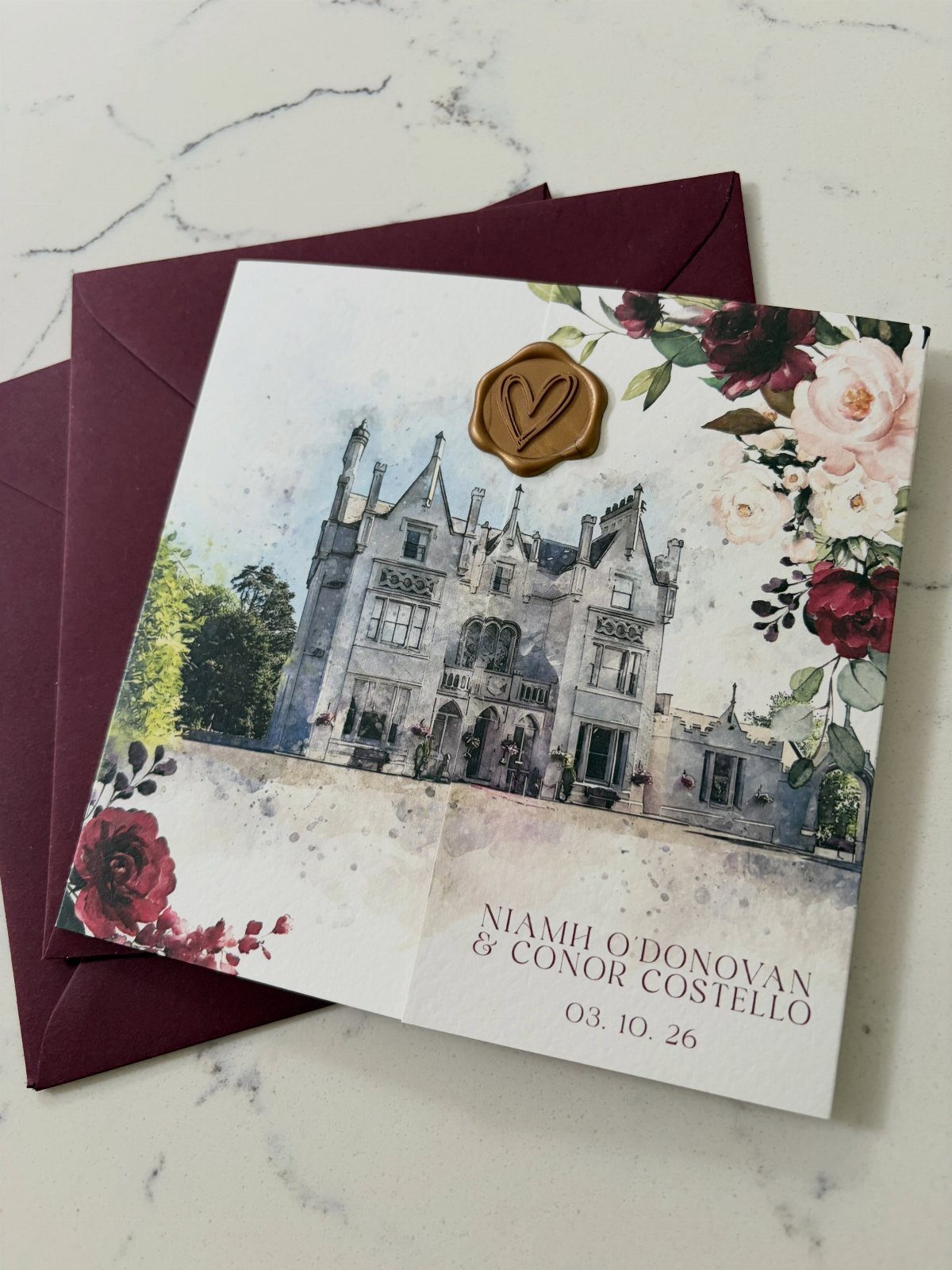 Wedding invitation with castle illustration, red roses, and gold heart wax seal.