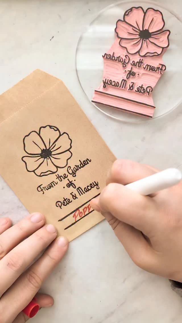 Brown paper seed envelope with a flower stamp being personalized by hand.