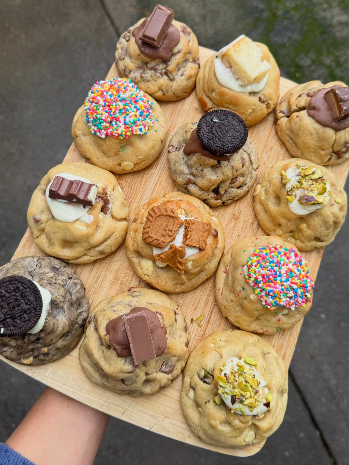 Assorted gourmet cookies with chocolate and sprinkles on a wooden serving board.