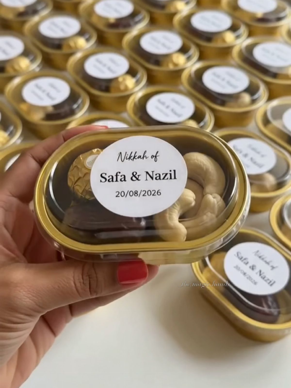 Gold-rimmed favor containers filled with chocolate and cashews for a wedding celebration.