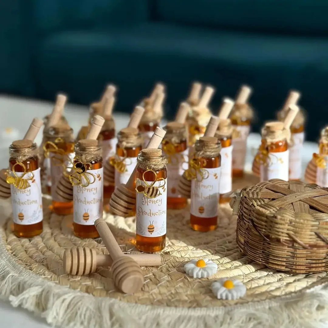 Small honey jars with wooden dippers arranged on a woven straw mat.