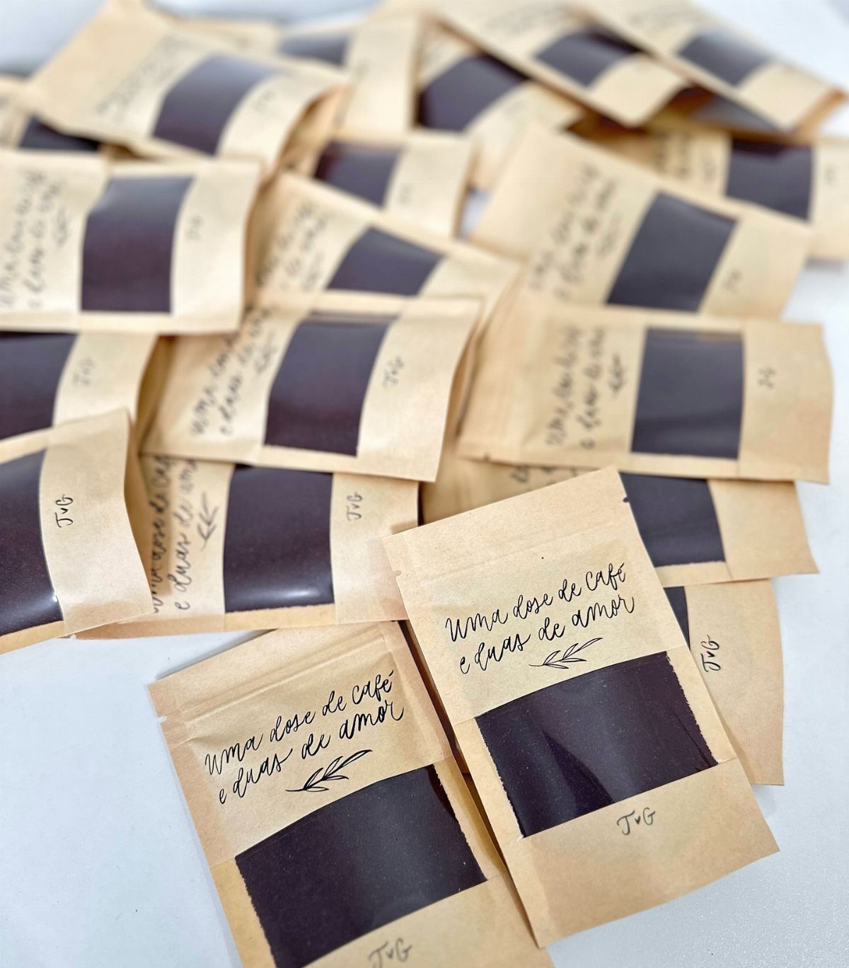 Small brown kraft paper coffee bags with handwritten text and clear windows.