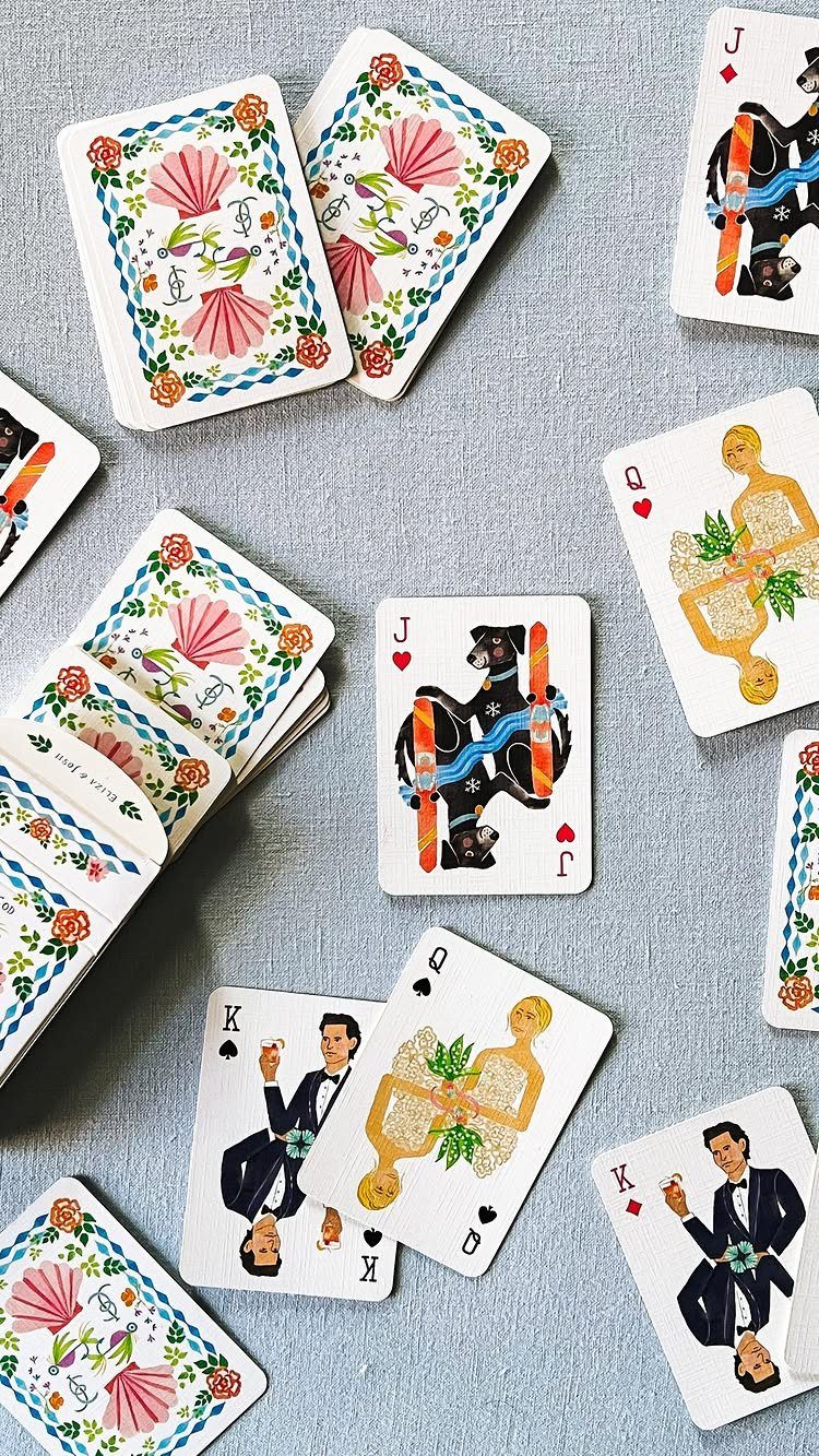 Custom playing cards with colorful illustrations scattered on a light grey surface.