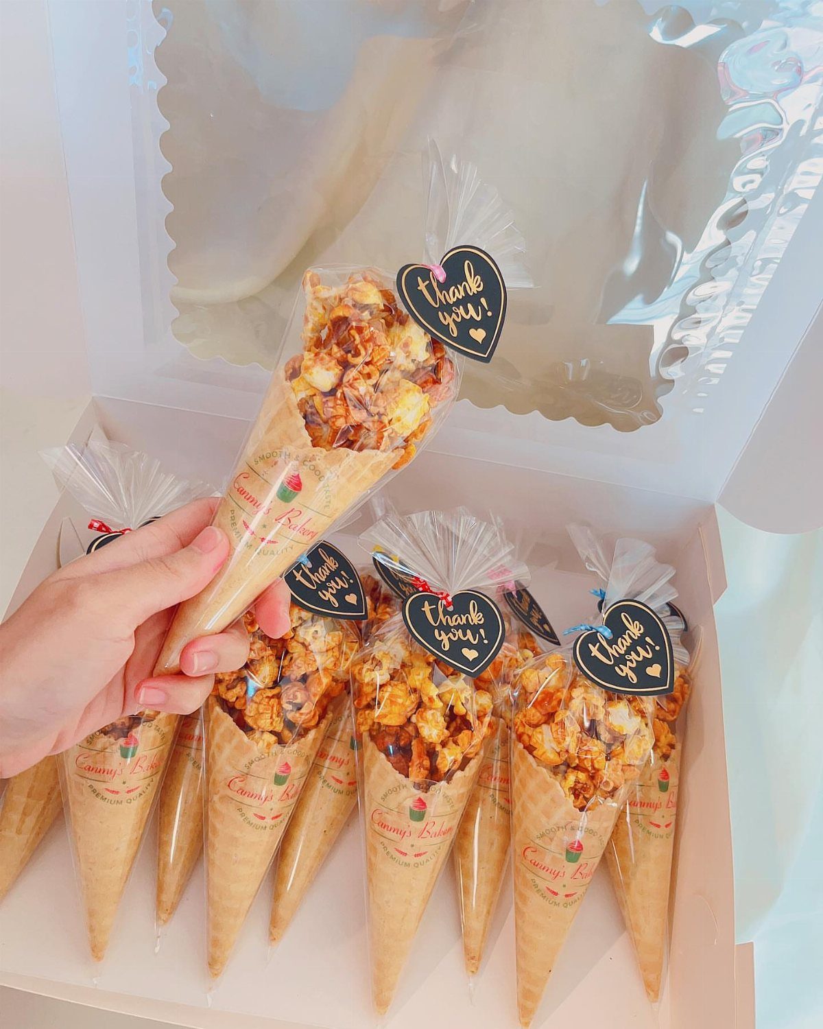 Caramel popcorn in paper cones with thank you tags inside a white box