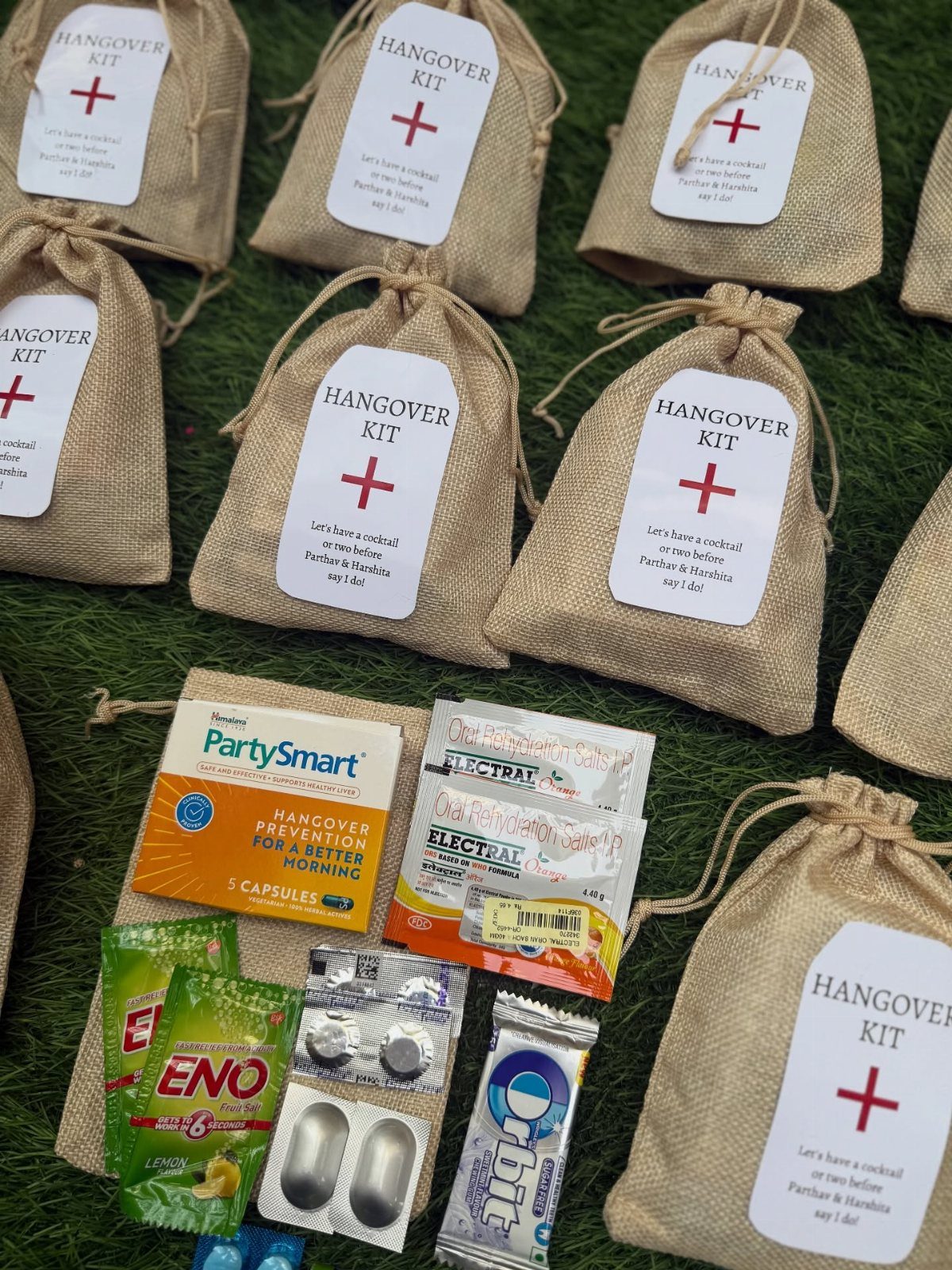 Burlap hangover kit bags with medical supplies and tags on green grass.