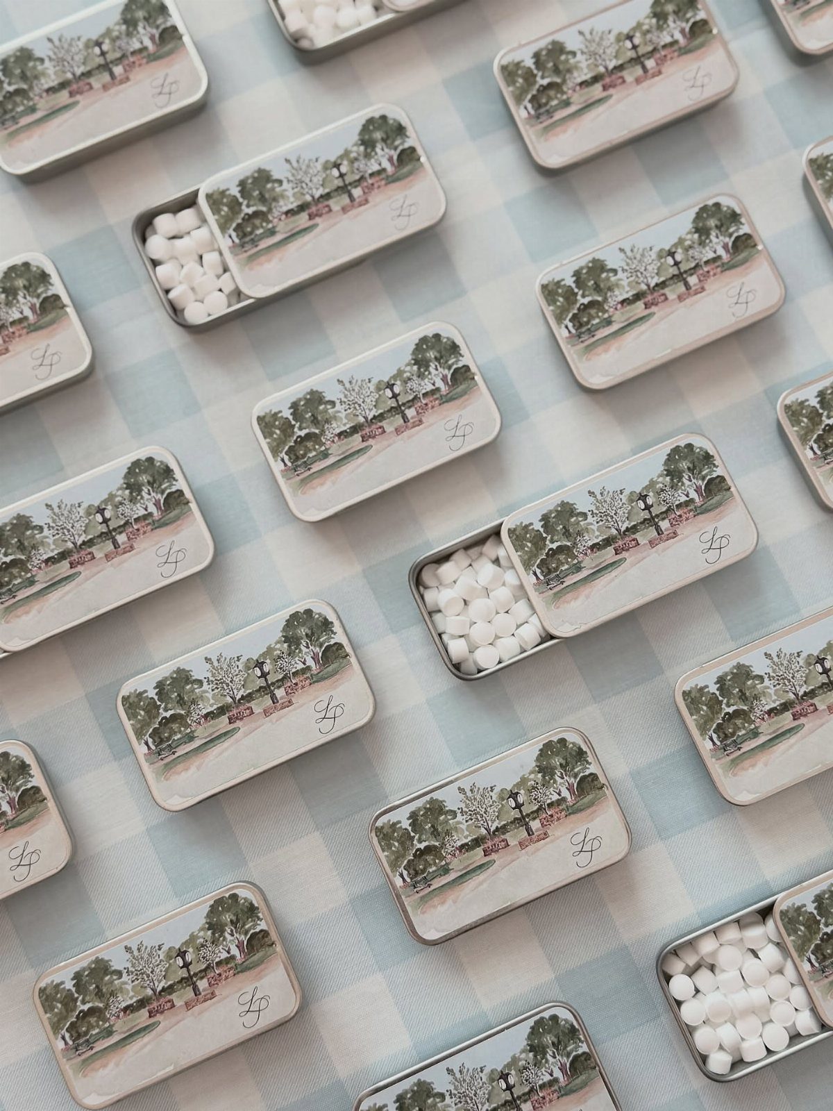 Small metal mint tins with illustrated lids on a blue checkered background
