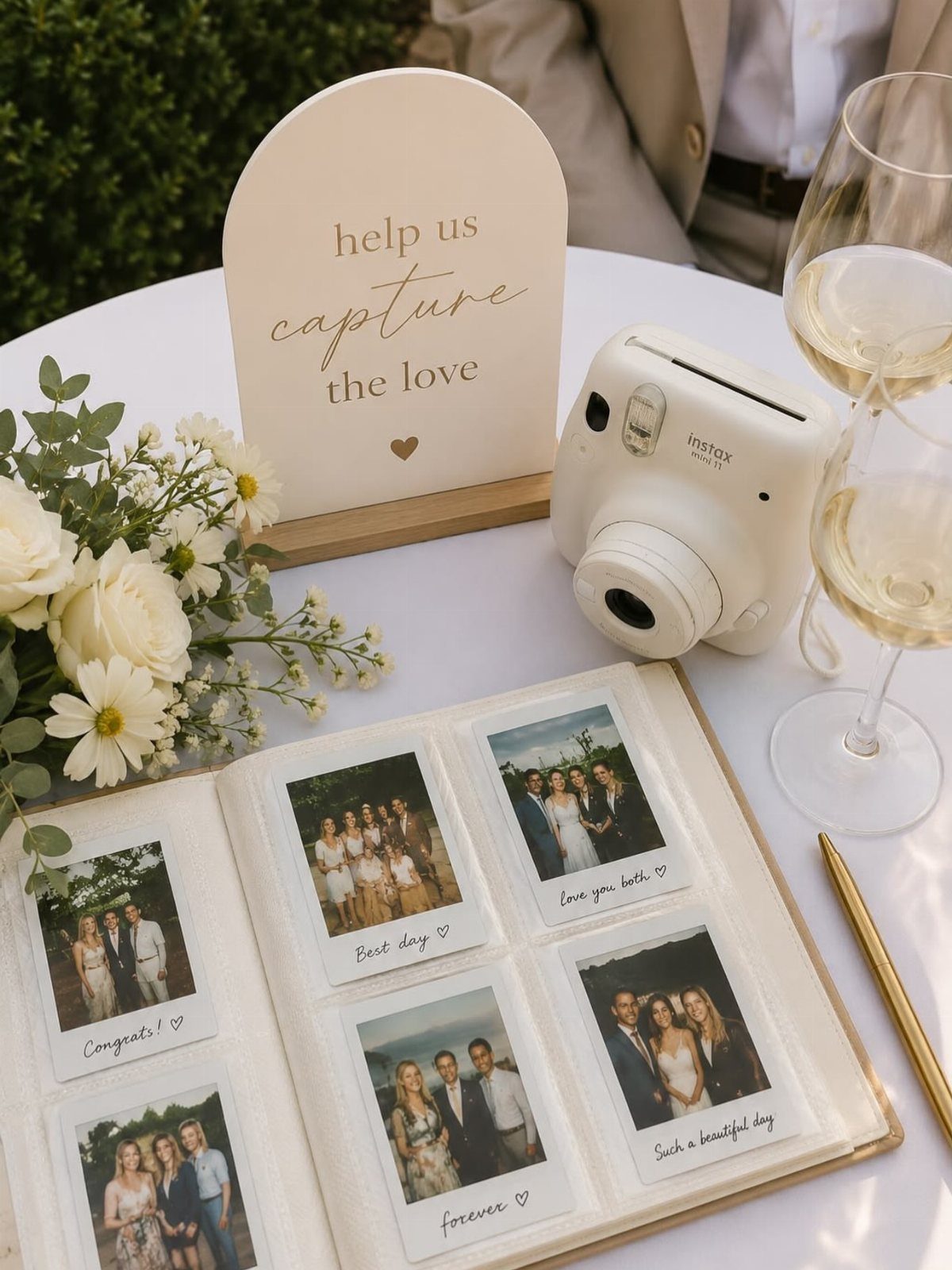 Polaroid camera and guest book with photos on a wedding table with flowers