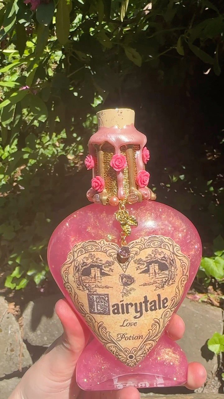 Heart-shaped bottle filled with pink shimmering liquid labeled as a Fairytale Love Potion