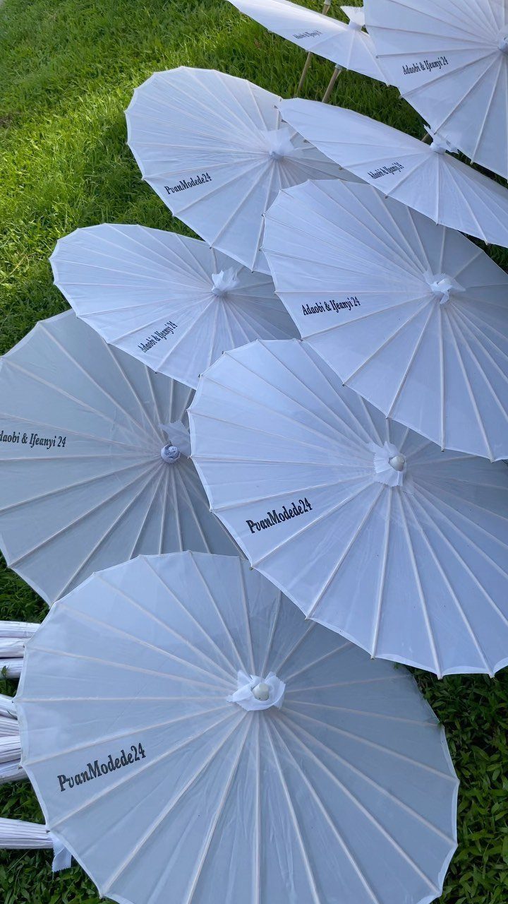 White paper umbrellas with custom text arranged on a green grass lawn.